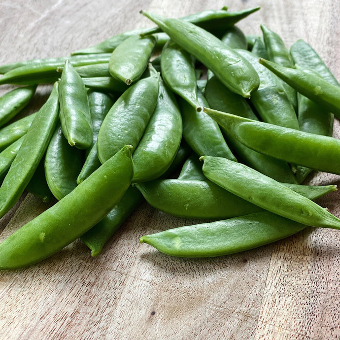 fresh sugarsnap peas on a wooden board