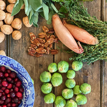 Load image into Gallery viewer, fresh brussell sprouts, shallot onions, pecans, cranberries, walnuts, thyme and sage on a wooden board
