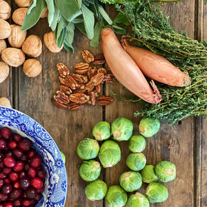 fresh brussell sprouts, shallot onions, pecans, cranberries, walnuts, thyme and sage on a wooden board